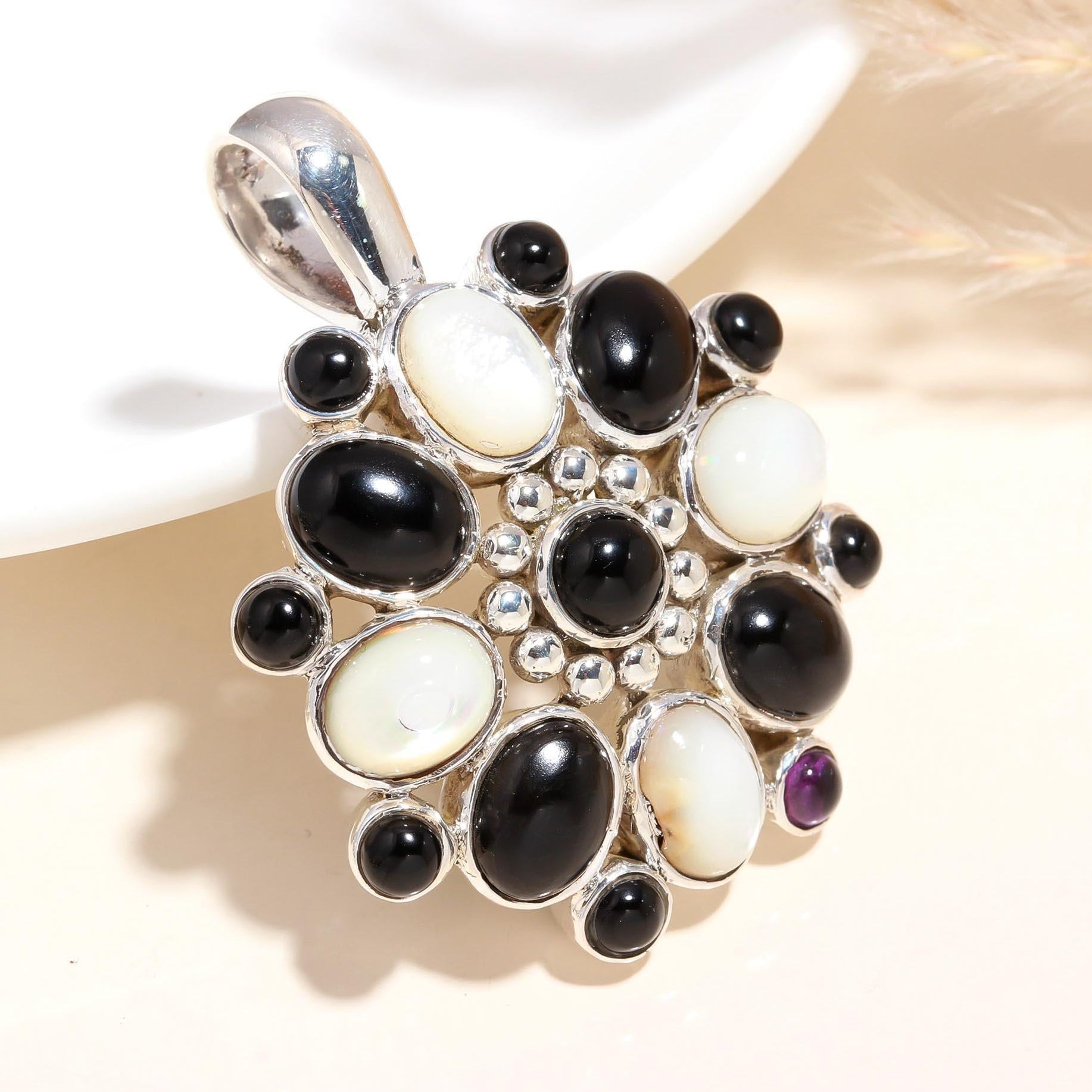 A vintage-inspired sterling silver pendant featuring black onyx and mother of pearl