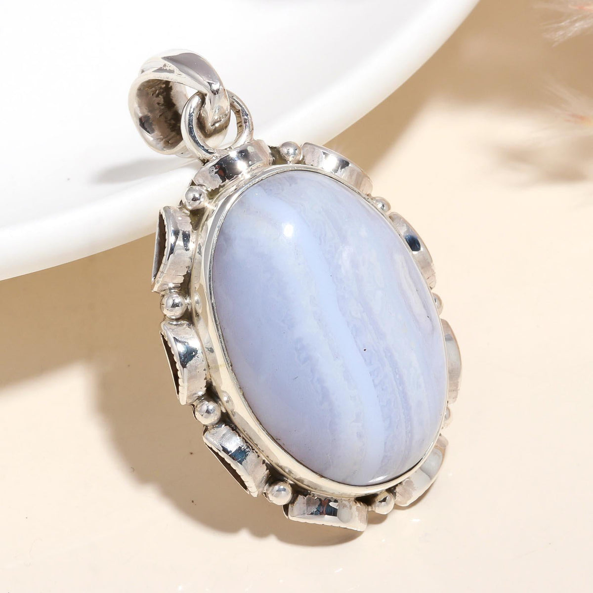 A sterling silver pendant featuring an oval-cut blue lace agate stone with a boho style design.