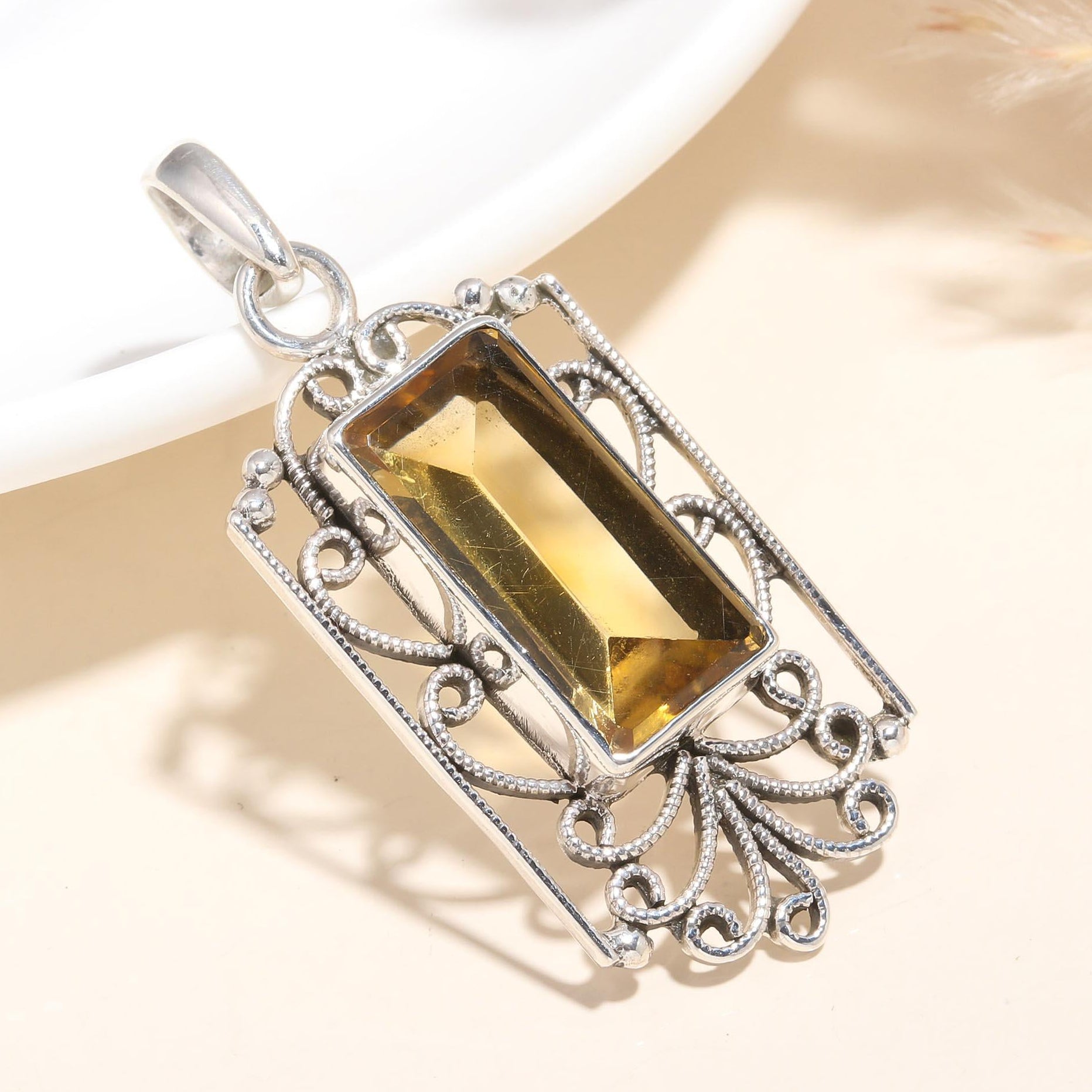 A rectangular citrine gemstone pendant set in a sterling silver vintage-style filigree setting, displayed against a neutral background.