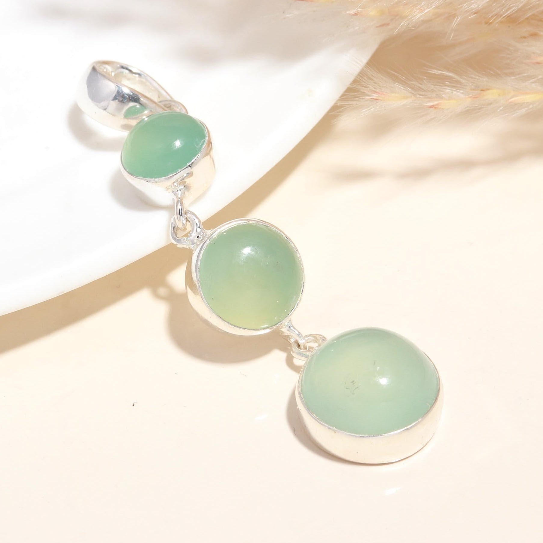 A sterling silver dangle pendant featuring natural green chalcedony gemstones, displayed against a neutral background.