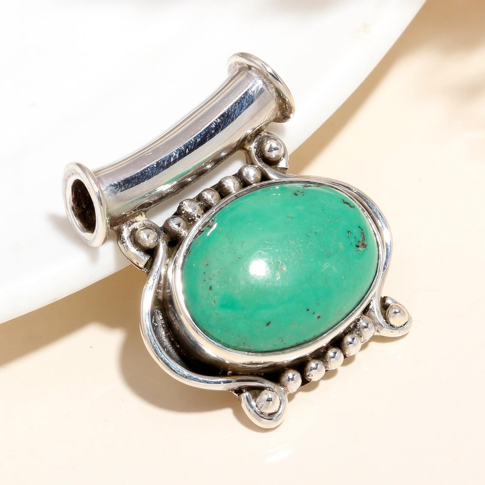 A vintage-inspired boho style sterling silver pendant with a natural green turquoise gemstone.
