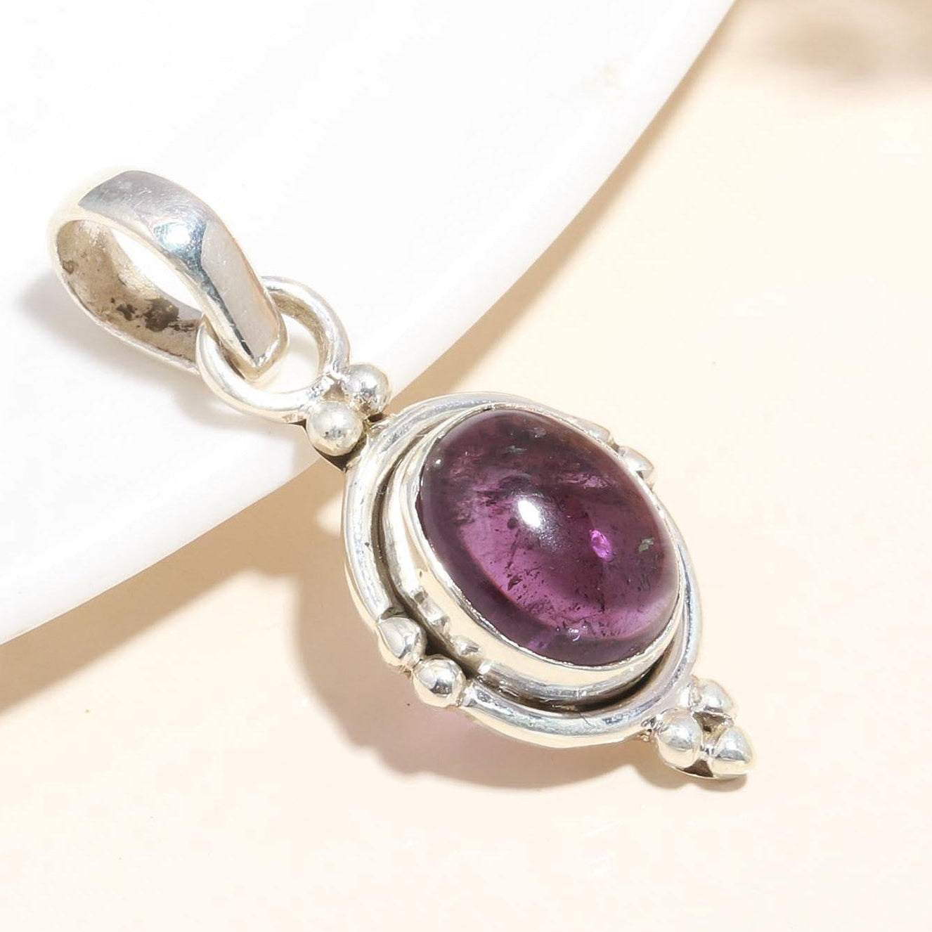 A 925 Sterling Silver Pendant with an oval-cut amethyst gemstone, presented on a white surface.