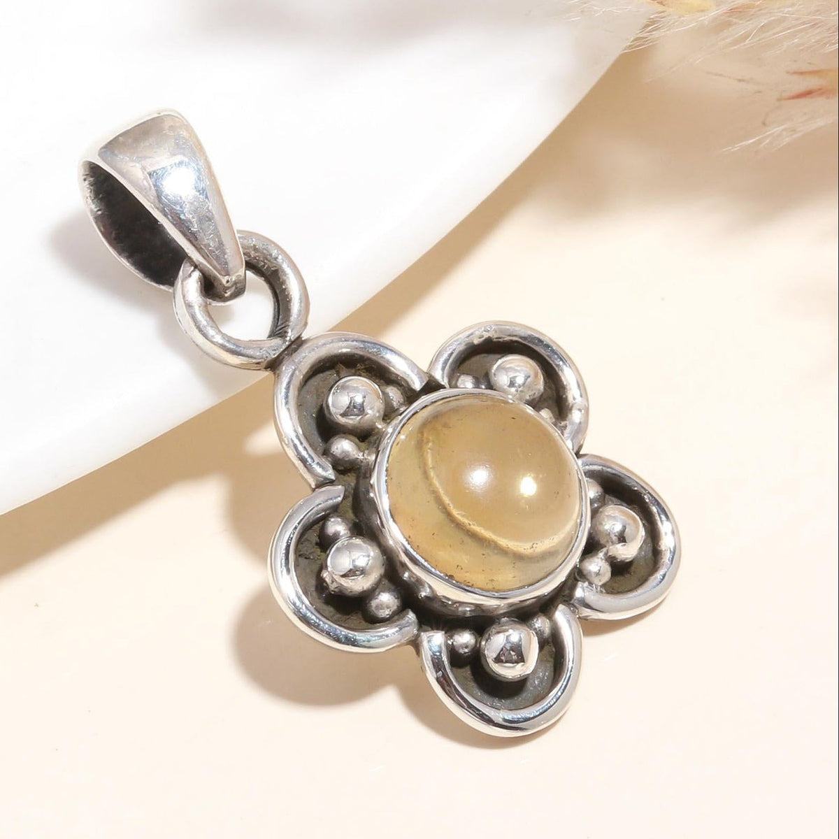 A floral boho pendant with a golden gemstone at its center, crafted in 925 sterling silver, displayed against a neutral background.
