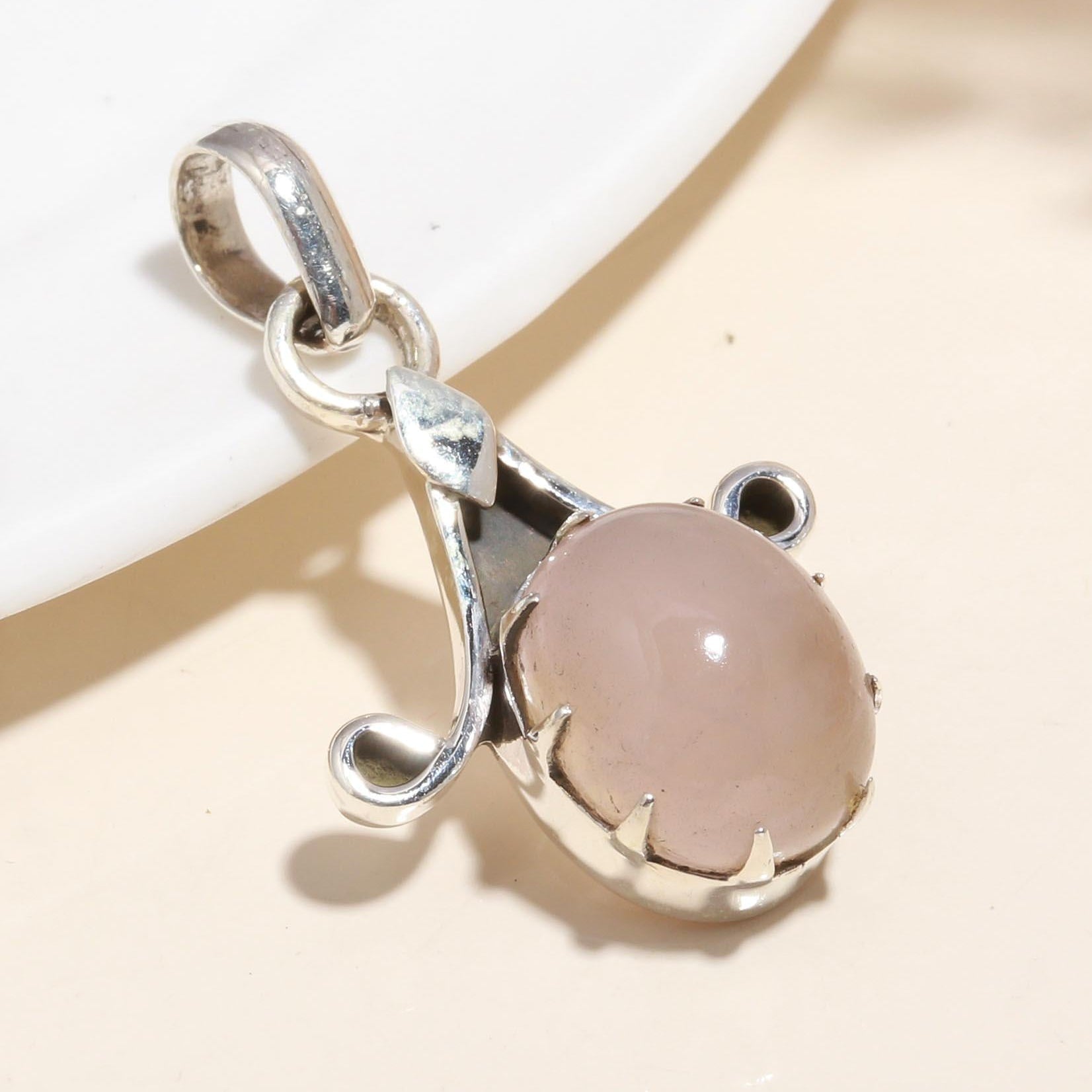 A 925 Sterling Silver pendant featuring a vintage-inspired design with a rose quartz gemstone at its center, presented against a neutral background.