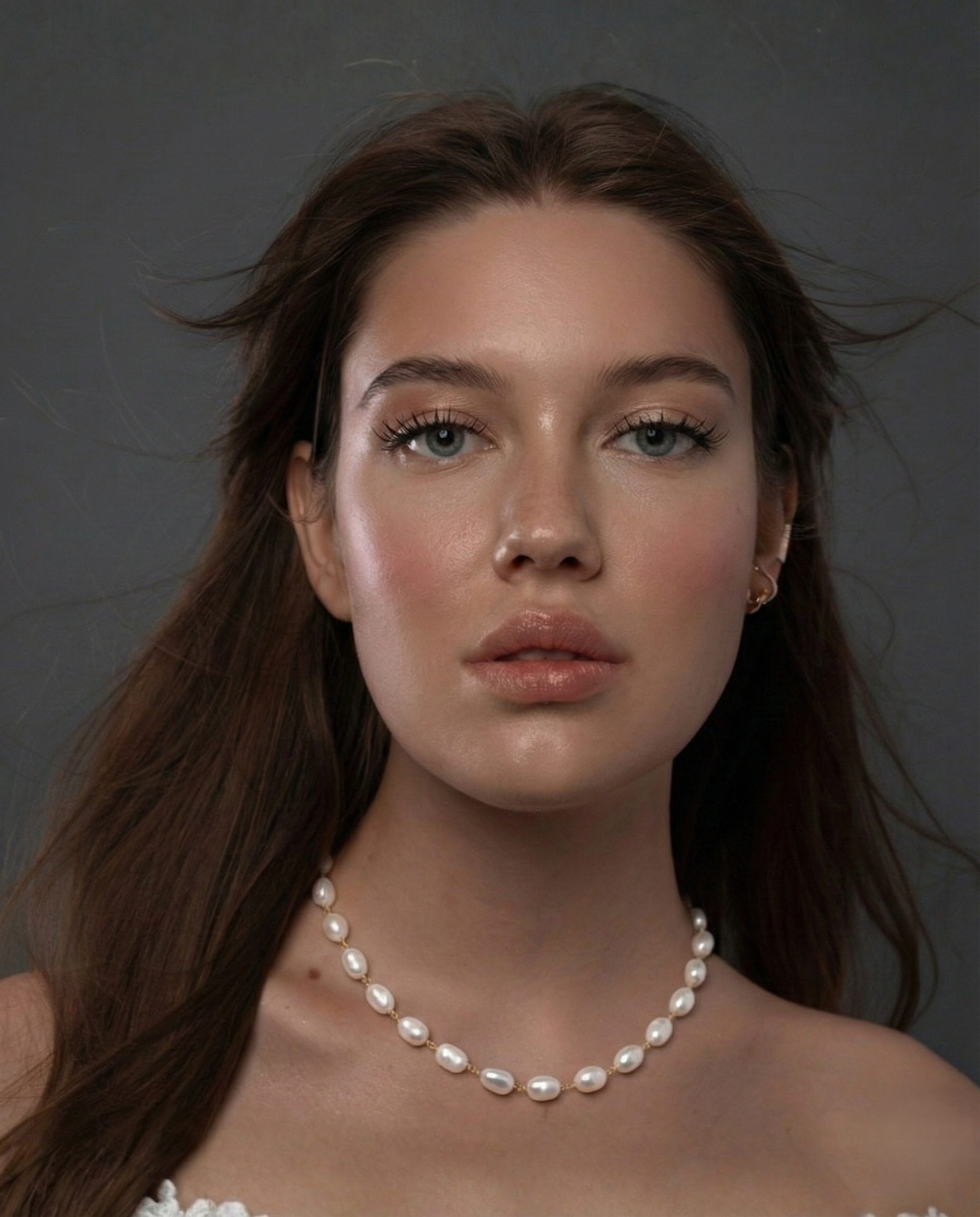 Woman wearing a pearl necklace against a neutral background