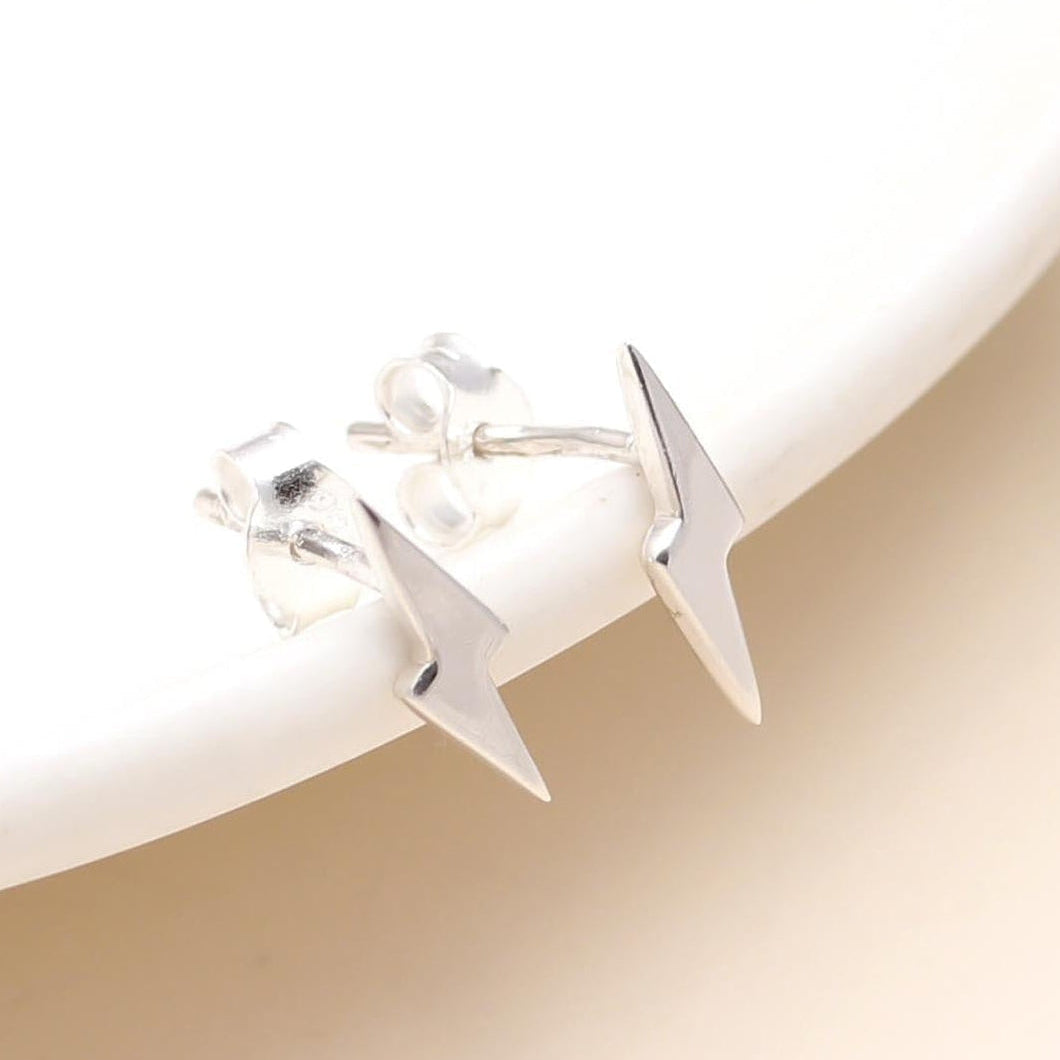 Silver triangle-shaped earrings on a light beige background