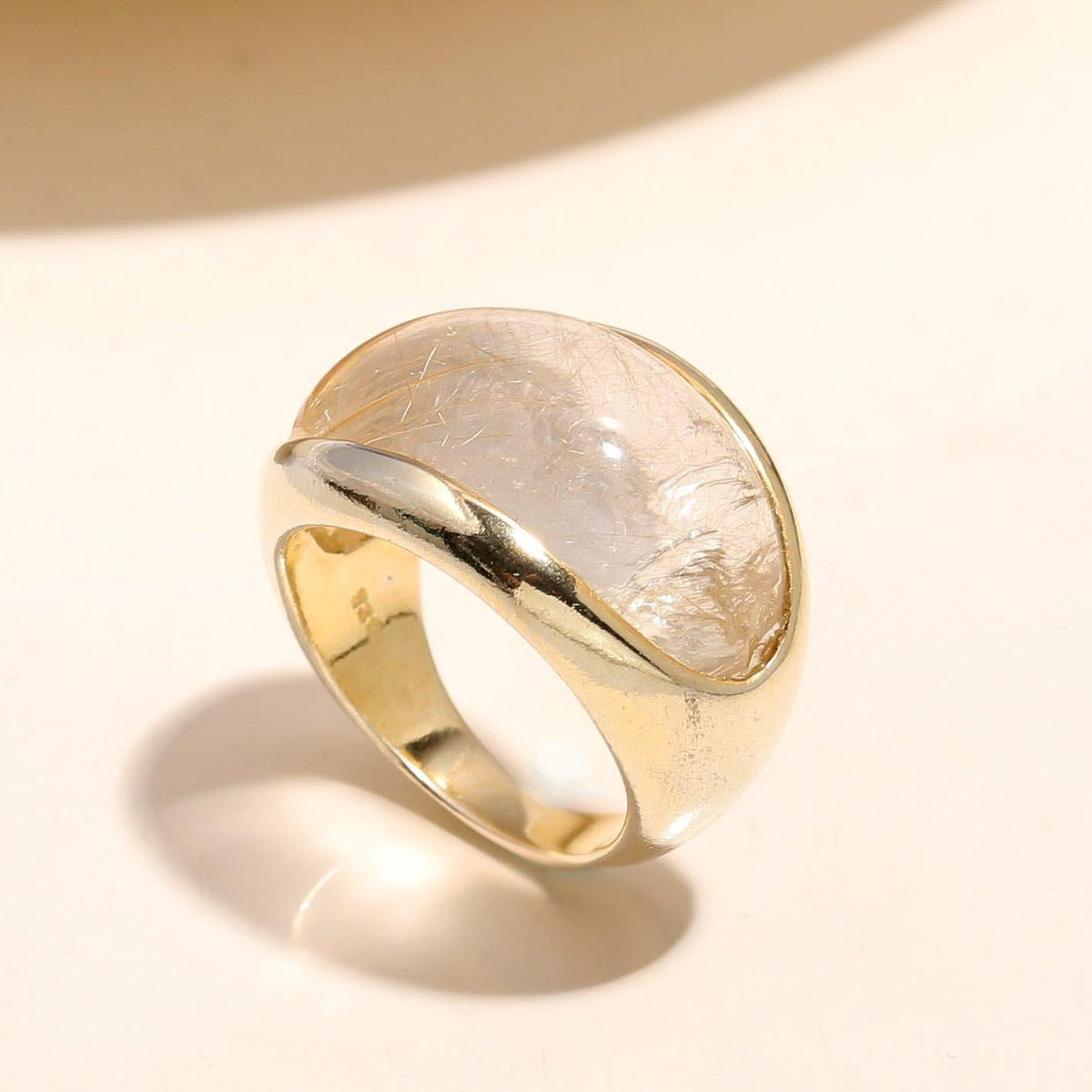 Gold ring with a textured surface on a light beige background