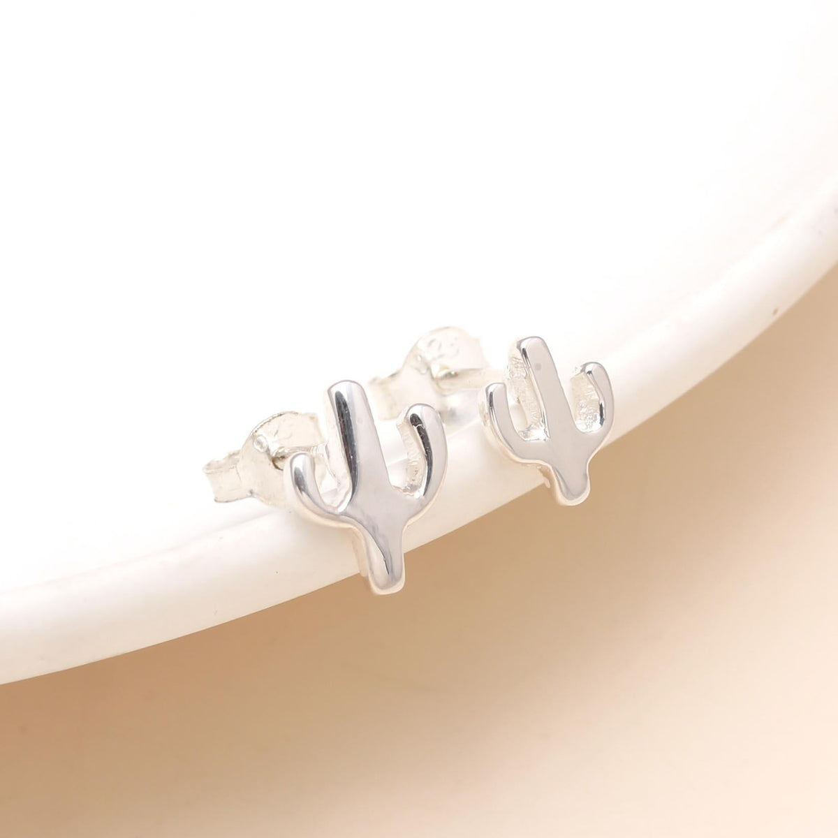 Silver earrings with 'MOM' on a beige background
